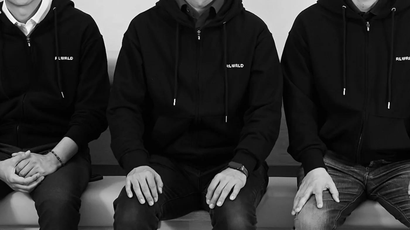 Team members wearing black hoodies with the RLWRLD logo